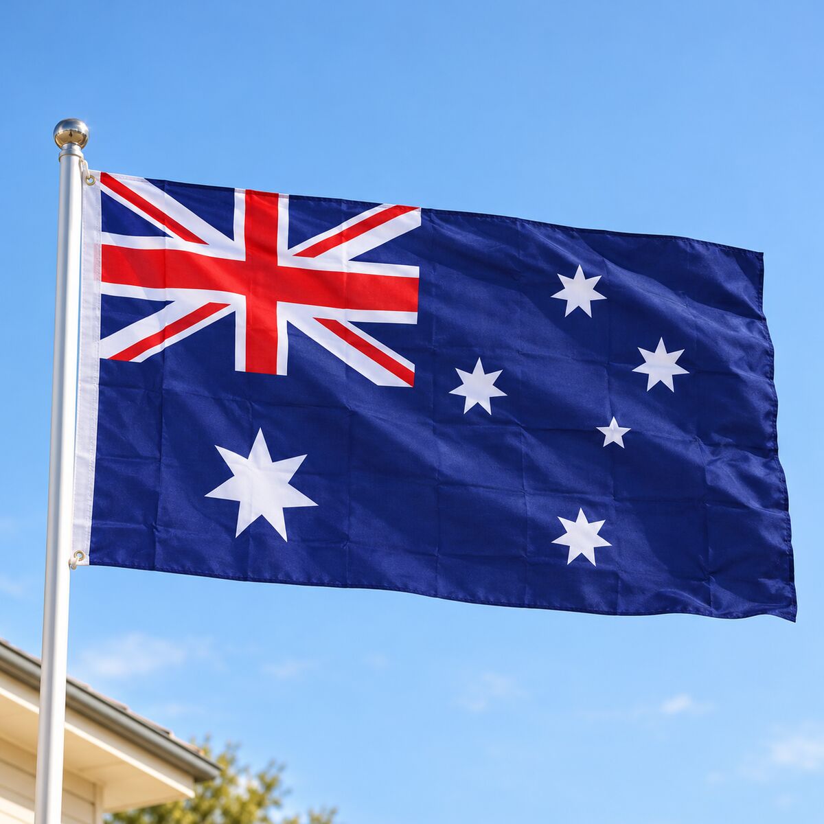Large Australian flag flying from a house flagpole against a clear blue sky.