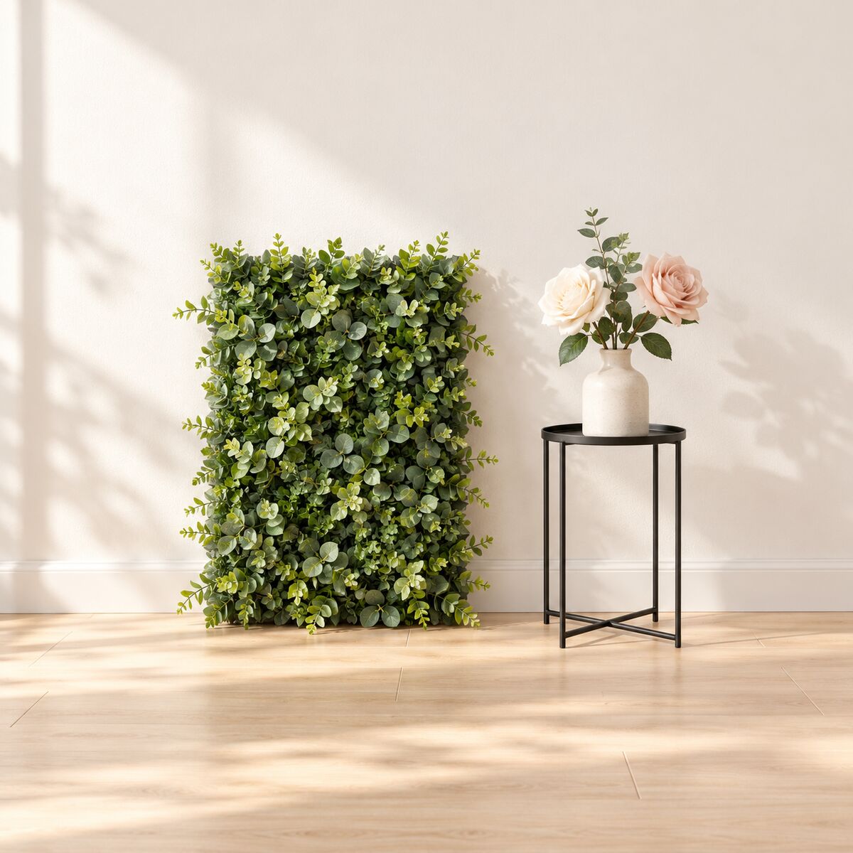 Artificial green wall panel section with silk roses in a bud vase and a black metal flower stand.