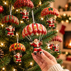Hand holding a wooden Santa parachute ornament beside a lit Christmas tree