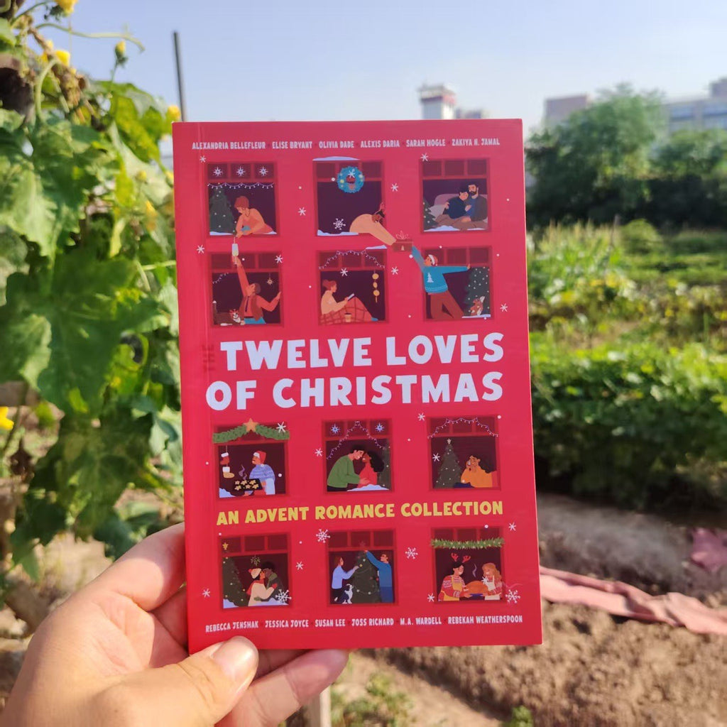 Hand holding The Twelve Loves of Christmas Christmas romance book in a garden