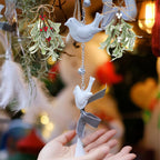 Hands holding artificial mistletoe with white berries beside hanging bird ornaments