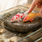 Two koi models on a rock in water