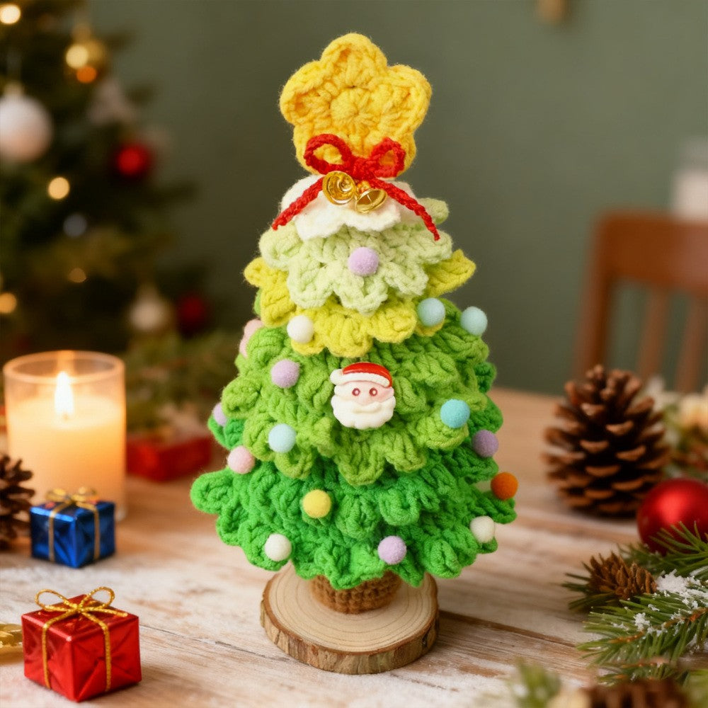 Light green crochet Christmas tree desk decoration beside candles and gift boxes