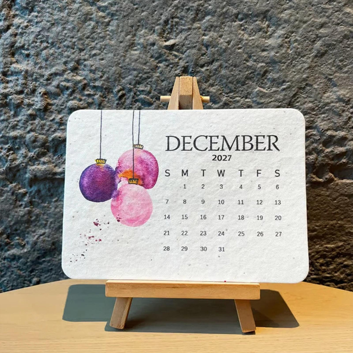 2027 plantable calendar December card on easel against a stone wall