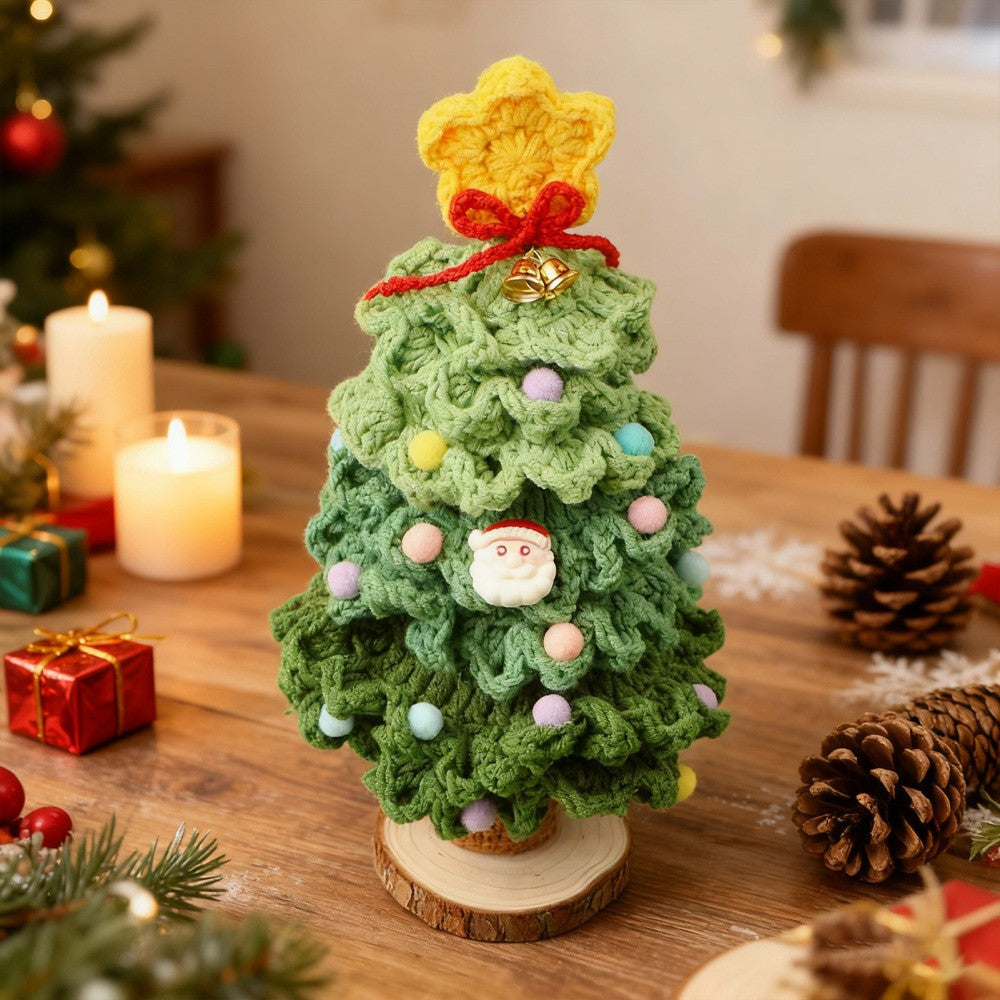 Dark green crochet mini Christmas tree on wooden table with pine cones and candles