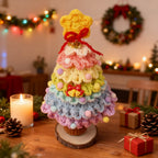 Rainbow crochet Christmas tree on a festive table with candles and wreath