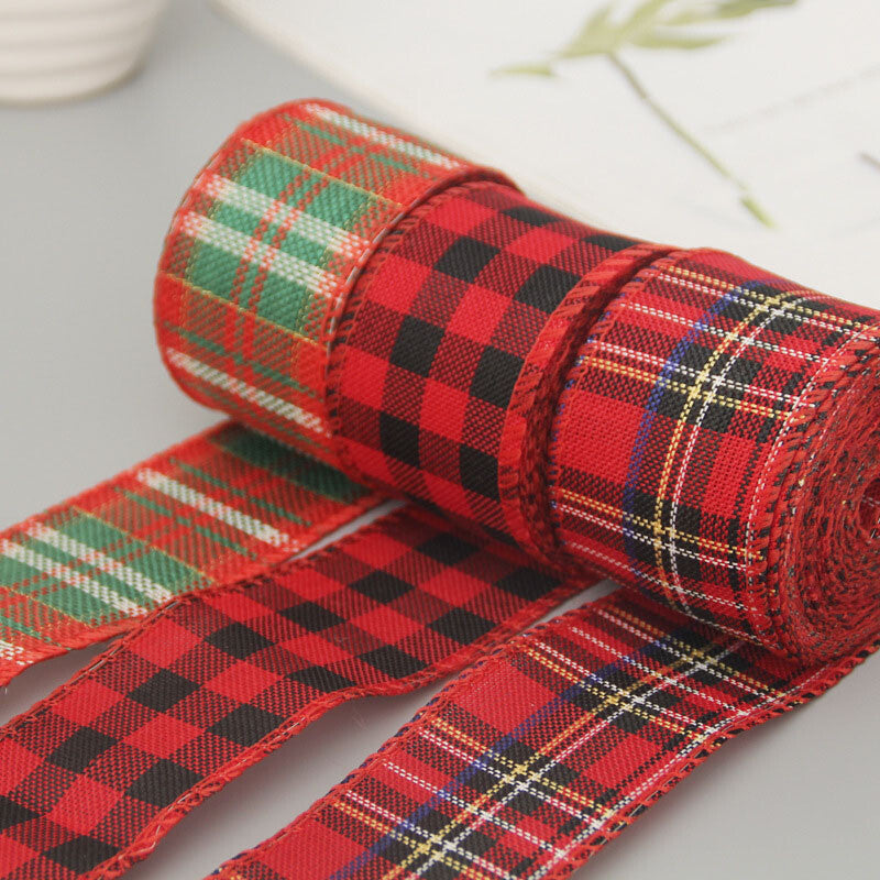 Red tartan wired Christmas ribbon rolls unrolled on a white table
