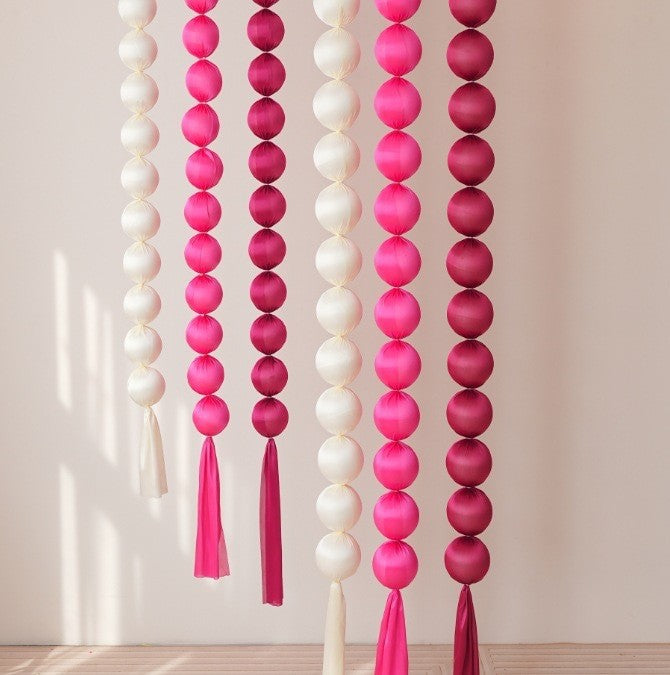 Pink and white ball garlands hanging on a wall